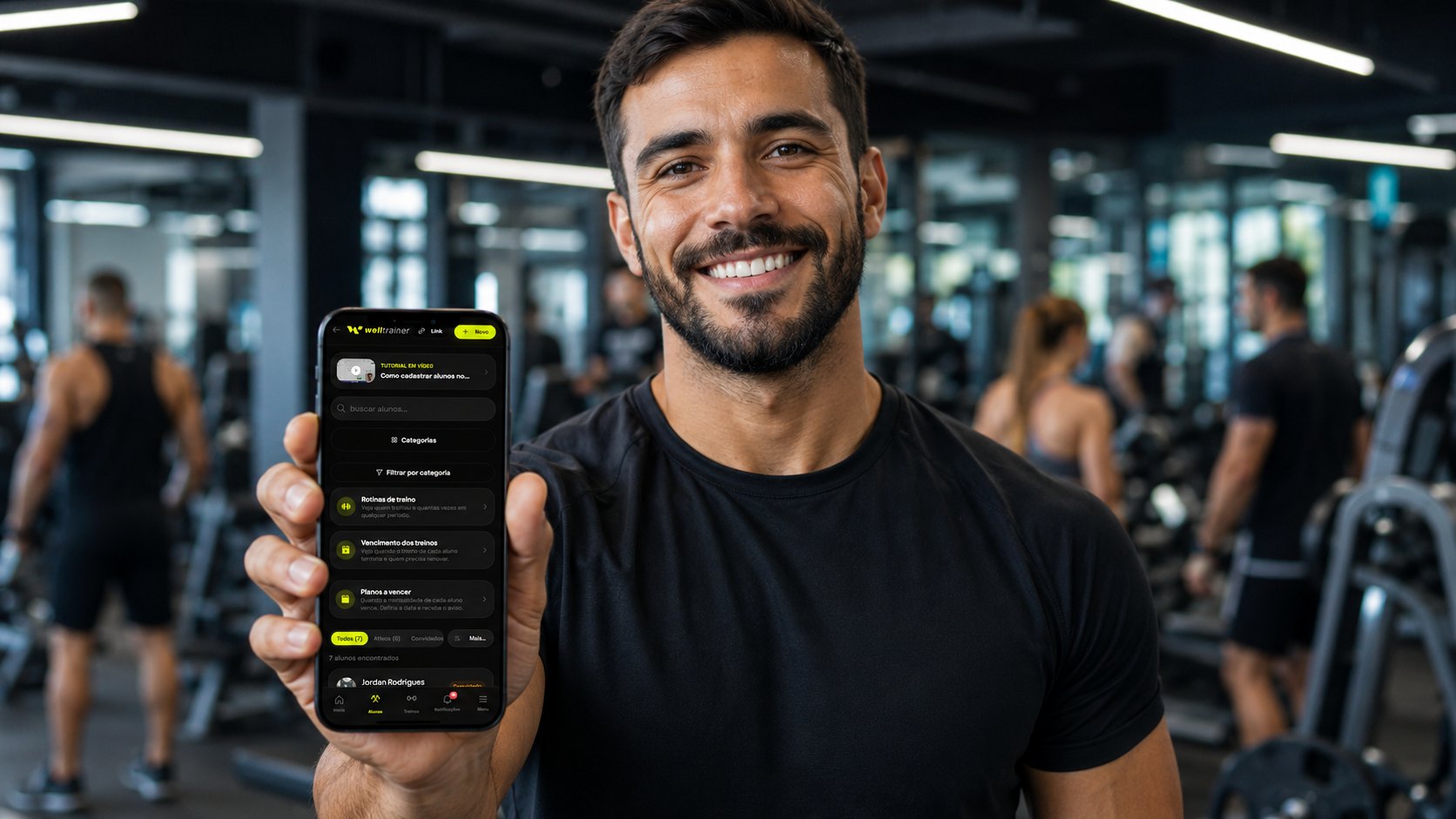 Personal trainer segurando o app Welltrainer com a lista de alunos numa academia cheia, escalar consultoria